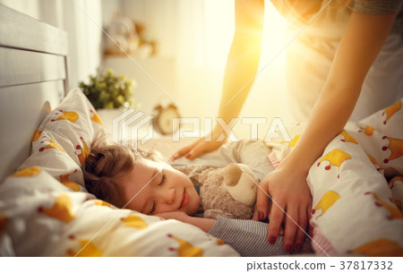 mother wakes up sleeping child daughter girl in morning. 37817332