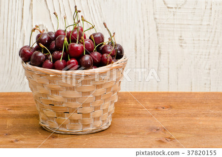 Basket with cherries on a wooden table Basket with cherries on a wooden table 37820155