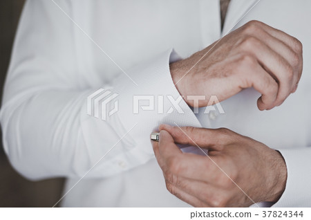 The process of putting the cufflinks on the sleeve of his shirt 7039. 37824344