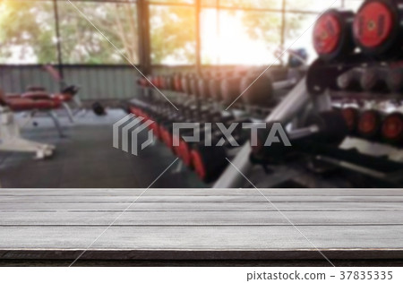 Wooden table on blurred background of fitness gym interior of mo Wooden table on blurred background of fitness gym interior of mo 37835335