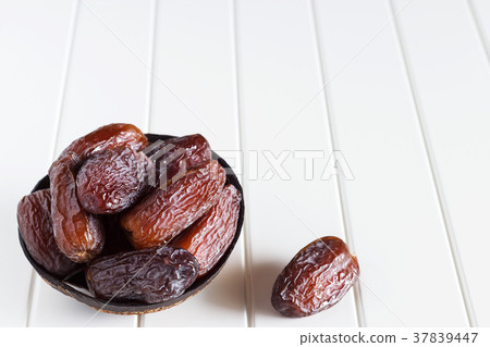 Fresh dates Medjool in wooden coconut bowl. Fresh dates Medjool in wooden coconut bowl. 37839447
