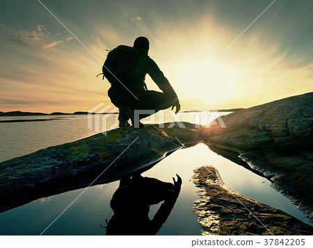 Man hiker sits alone on coast and enjoy sunset. 37842205