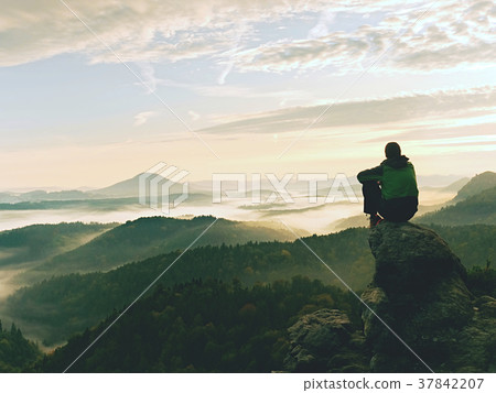 Hiker man take a rest on mountain peak. Man sit Hiker man take a rest on mountain peak. Man sit 37842207