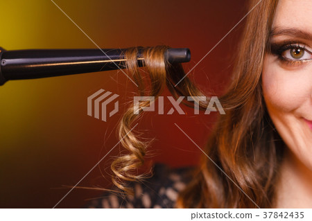 Happy woman curling her long brown hair 37842435