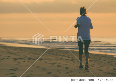 Old woman is running by the beach at sunrise. Old woman is running by the beach at sunrise. 37843028