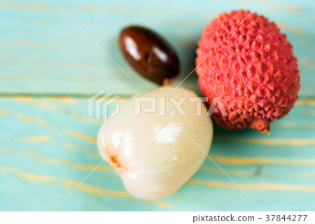 Two lychee fruits and seed wooden background Two lychee fruits and seed wooden background 37844277