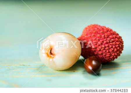 Two lychee fruits and seed wooden background Two lychee fruits and seed wooden background 37844283