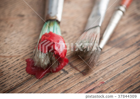 red acrylic paint on brush on wooden table red acrylic paint on brush on wooden table 37844309