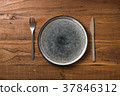 Plate on brown wooden background with utensils 37846312