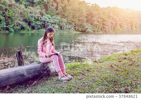 Young girl reading a book in the park. Young girl reading a book in the park. 37848621