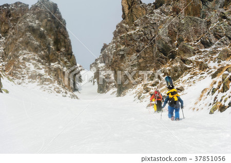 Extreme skiers climb to the top along the couloir 37851056