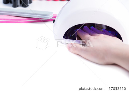 Woman put hand in led lamp dryer on white table 37852330