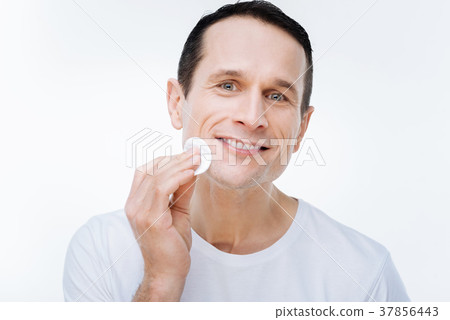 Pleasant nice man holding a cotton pad 37856443