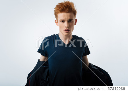 Red-headed man taking off a black jacket 37859086