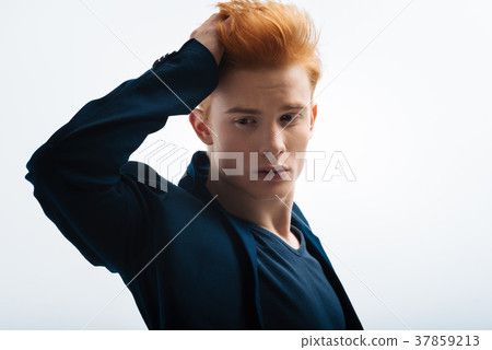 Unsmiling man touching his hair 37859213