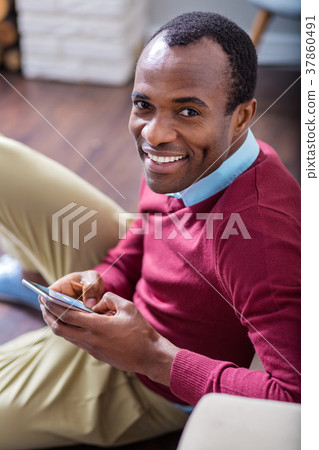 Cheerful handsome man using his mobile device Cheerful handsome man using his mobile device 37860491