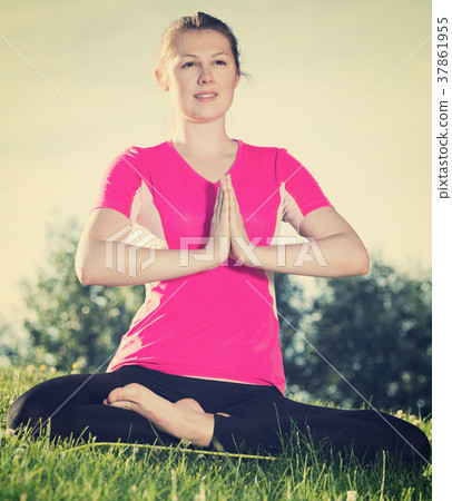 Girl in pink T-shirt is sitting and meditating 37861955