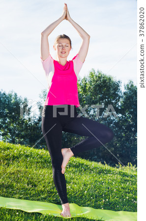 Young girl in pink T-shirt is staying and practising meditation 37862020