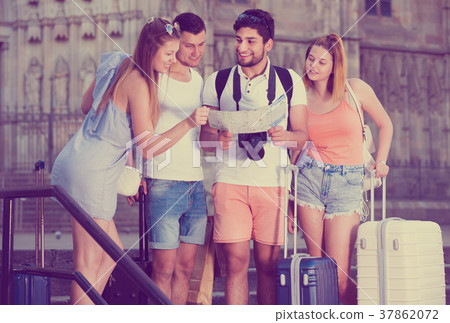 Group of young traveling people using paper map in city Group of young traveling people using paper map in city 37862072