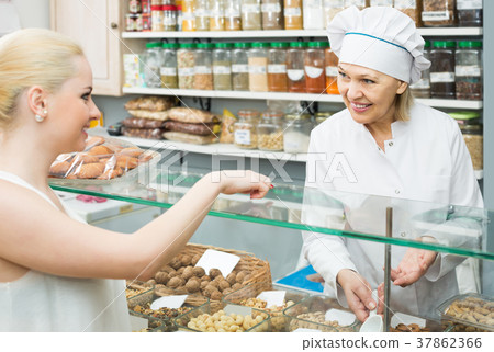 Satisfied woman buying different nuts in local supermarket Satisfied woman buying different nuts in local supermarket 37862366