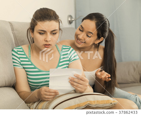 Girls reading billet-doux on sofa Girls reading billet-doux on sofa 37862433