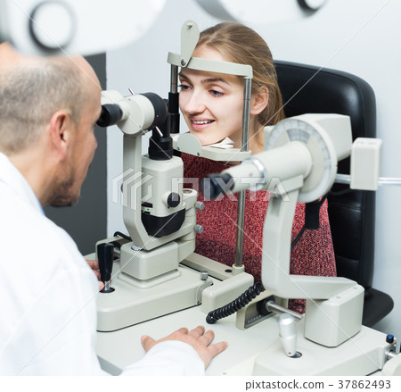 Ophthalmologist and girl checking eyesight Ophthalmologist and girl checking eyesight 37862493