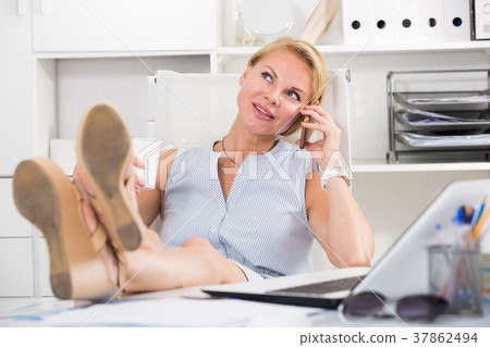 Portrait of blond female in office talking on mobile Portrait of blond female in office talking on mobile 37862494