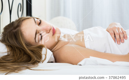 woman lying in bed under sheet with closed eyes 37862495