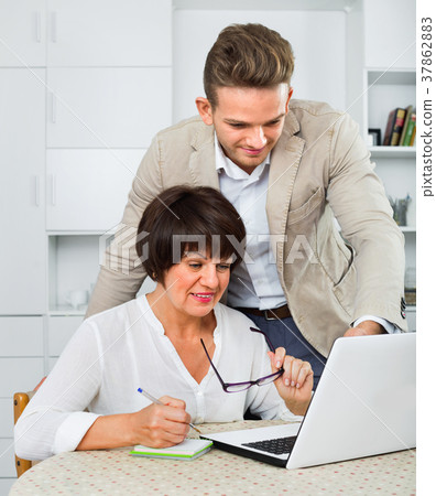 Son shows to his elderly mother new software on laptop 37862883