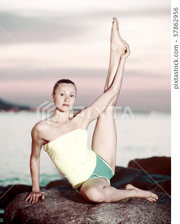 woman in sportwear doing exercises at sunset sea shore 37862956