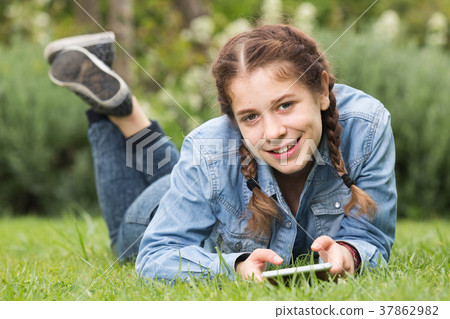 teen using digital tablet while lying in summer park 37862982