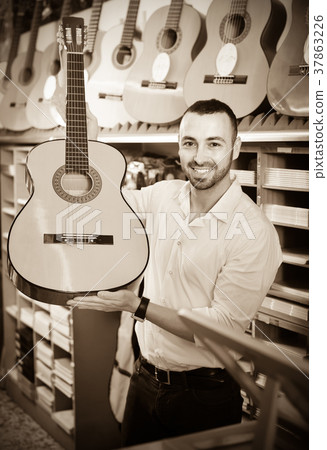 Guy choosing guitar in music shop. 37863226