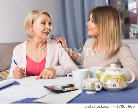 Daughter helps mother to lead home accounting Daughter helps mother to lead home accounting 37863669
