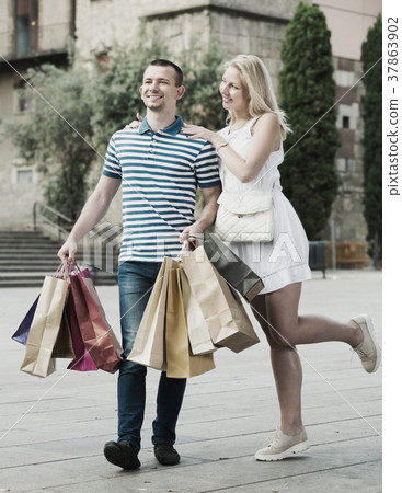 Young couple carrying few paper bags outdoors Young couple carrying few paper bags outdoors 37863902