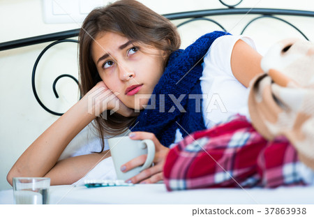 Sick teenage girl with hot tea and medication indoors 37863938
