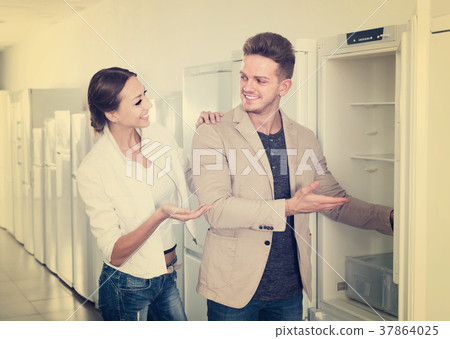 interested couple choosing new refrigerator in hypermarket 37864025