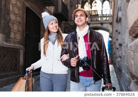 Portrait of adult tourists walking in hats and scarfs with bags Portrait of adult tourists walking in hats and scarfs with bags 37864028
