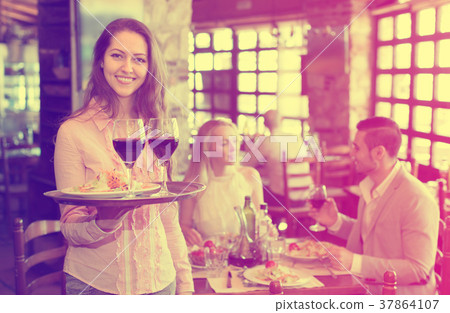 Waiter with restaurant guests at table 37864107