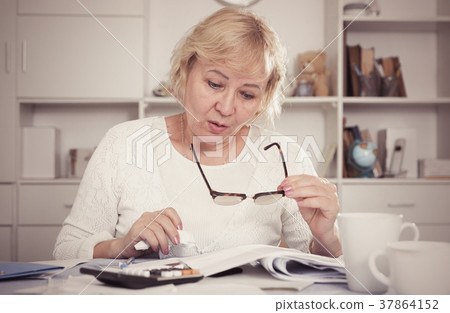 Woman engaged in home accounting Woman engaged in home accounting 37864152