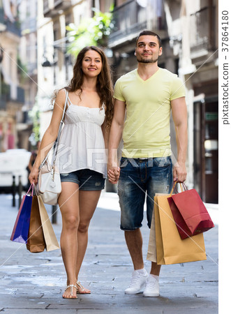Smiling young pair with shopping pack at city Smiling young pair with shopping pack at city 37864180