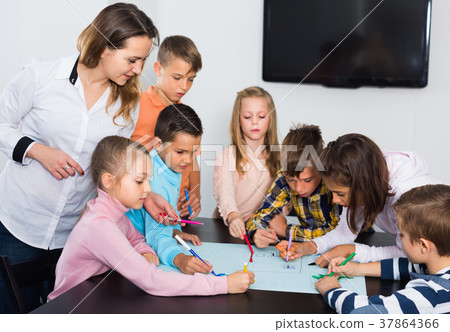 Children with teacher drawing together in classroom Children with teacher drawing together in classroom 37864366