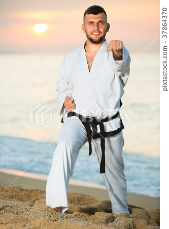 Young sportsman is practicing karate moves Young sportsman is practicing karate moves 37864370
