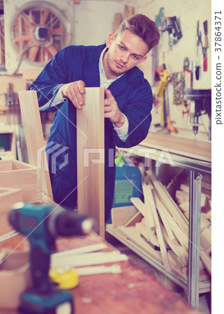 Man measuring boards for furniture at workshop Man measuring boards for furniture at workshop 37864371