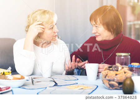 Two serious elderly women discussing 37864828