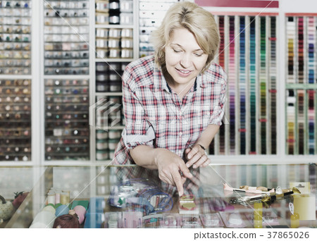 portrait of female cashier standing at cash desk in embroidery shop 37865026