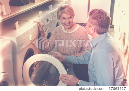 Pretty mature married couple are choosing washing machine Pretty mature married couple are choosing washing machine 37865317