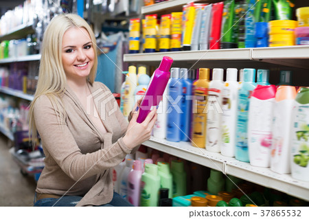 Happy young woman choosing hair conditioner 37865532