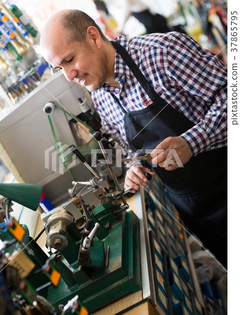 Mature man making duplicates of keys . 37865795