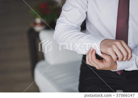 Young man buttons cuff link on the sleeve of his shirt 7947. Young man buttons cuff link on the sleeve of his shirt 7947. 37866147