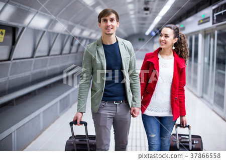 Portrait of couple with wheeled trollers at subway platform Portrait of couple with wheeled trollers at subway platform 37866558